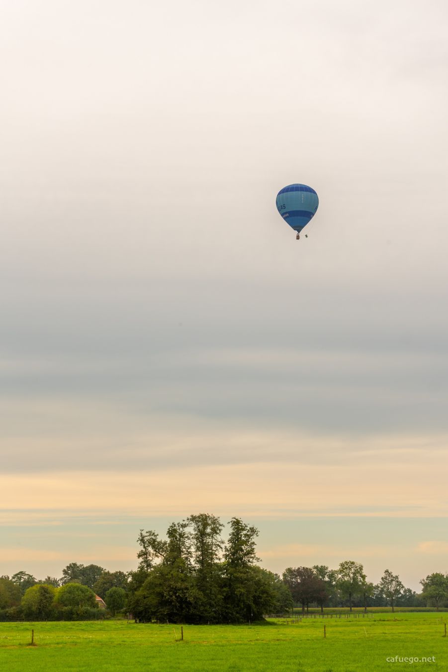 Balloon against a colourful evening sky over a rural landscape.