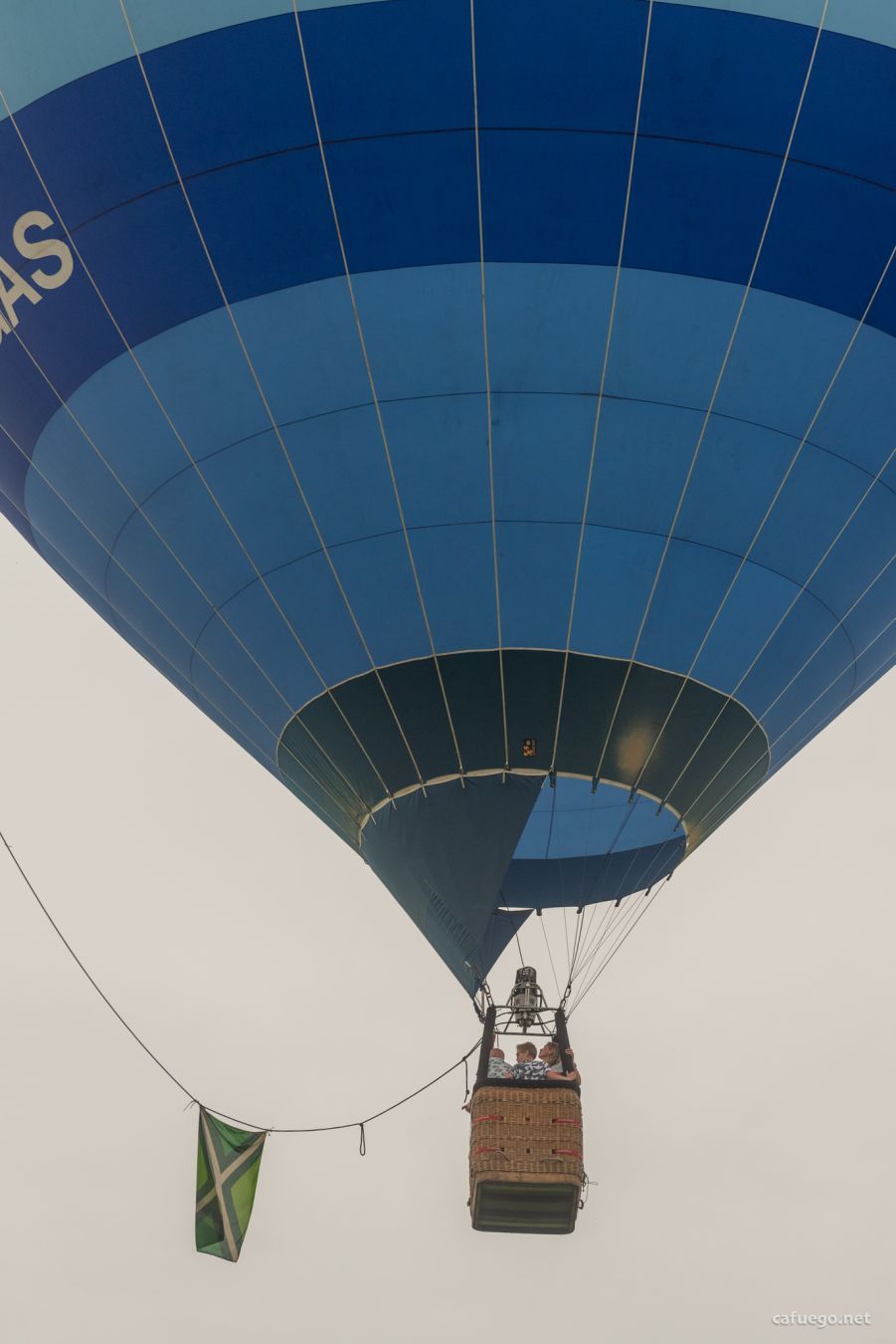 Basket full of waving people under a balloon.