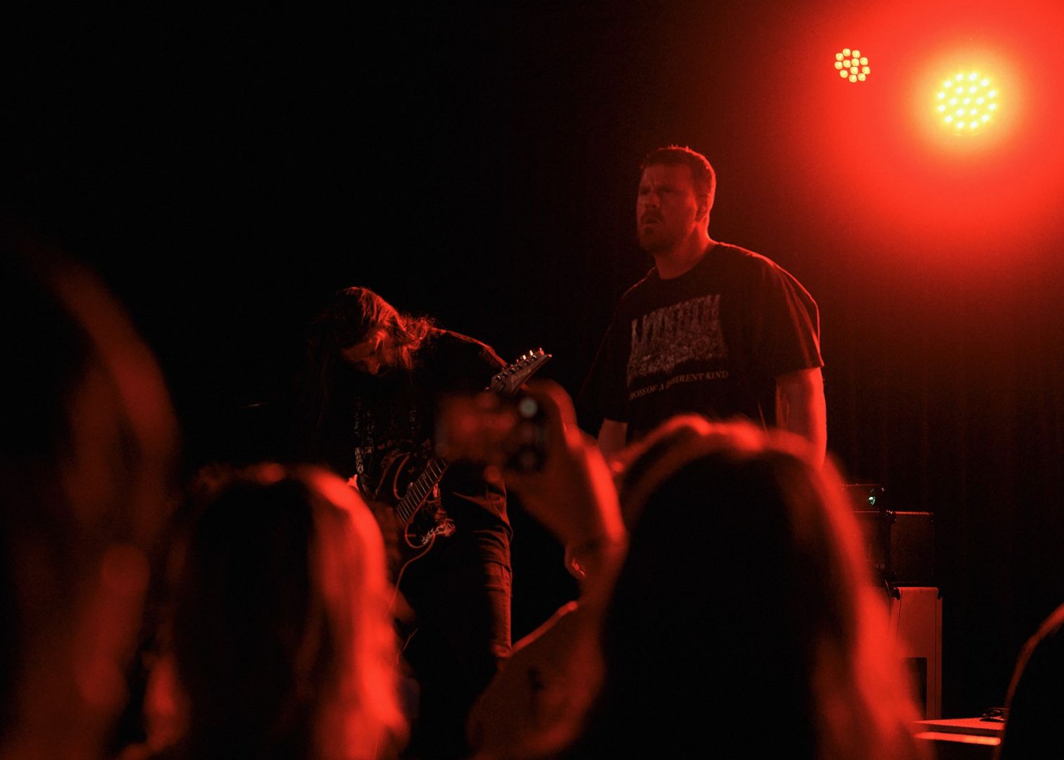 Resin Tomb's vocalist and guitarist on stage with a few crowd members in the foreground.