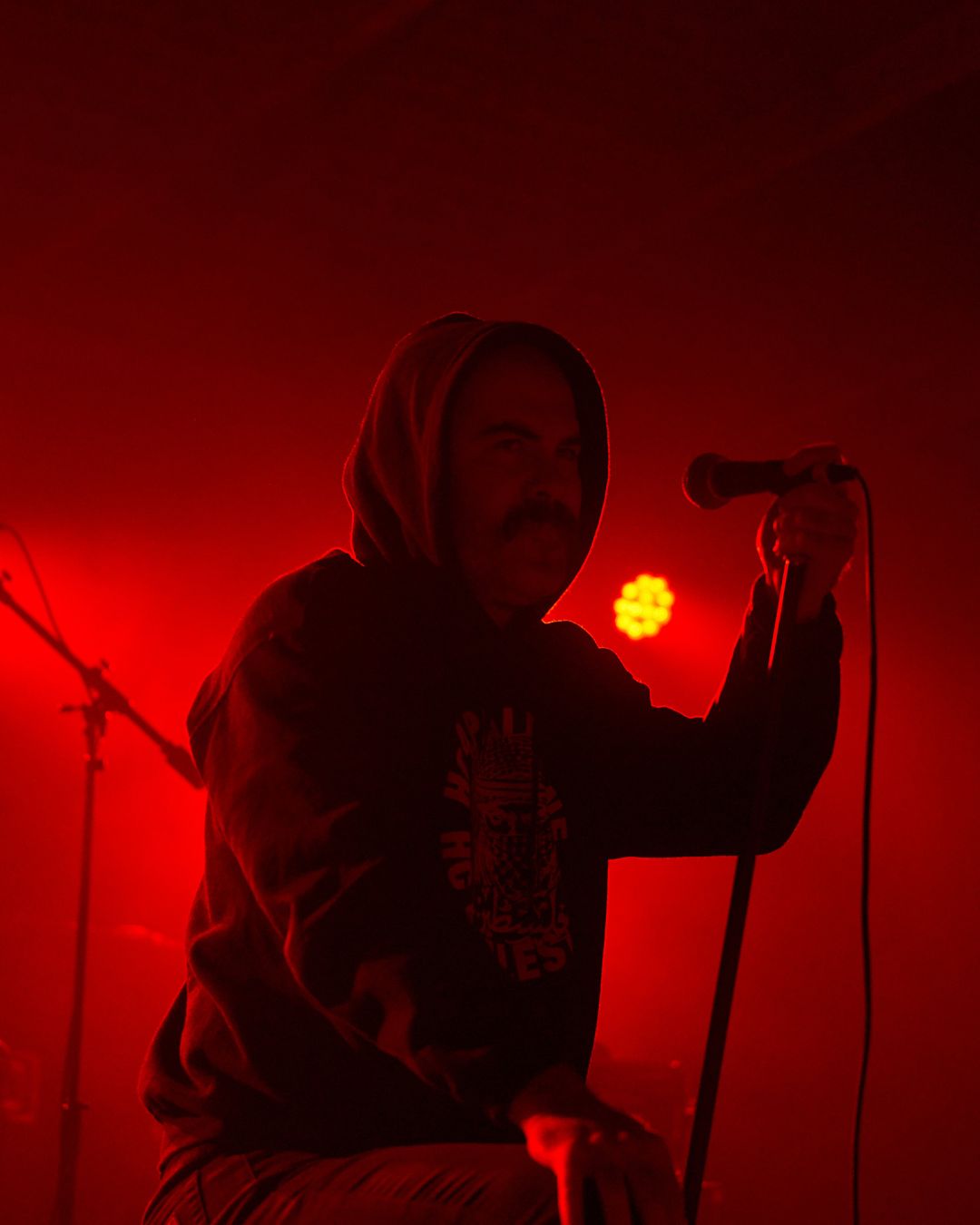 slowcut's vocalist surveys the crowd, he is backlit by intense red lighting.