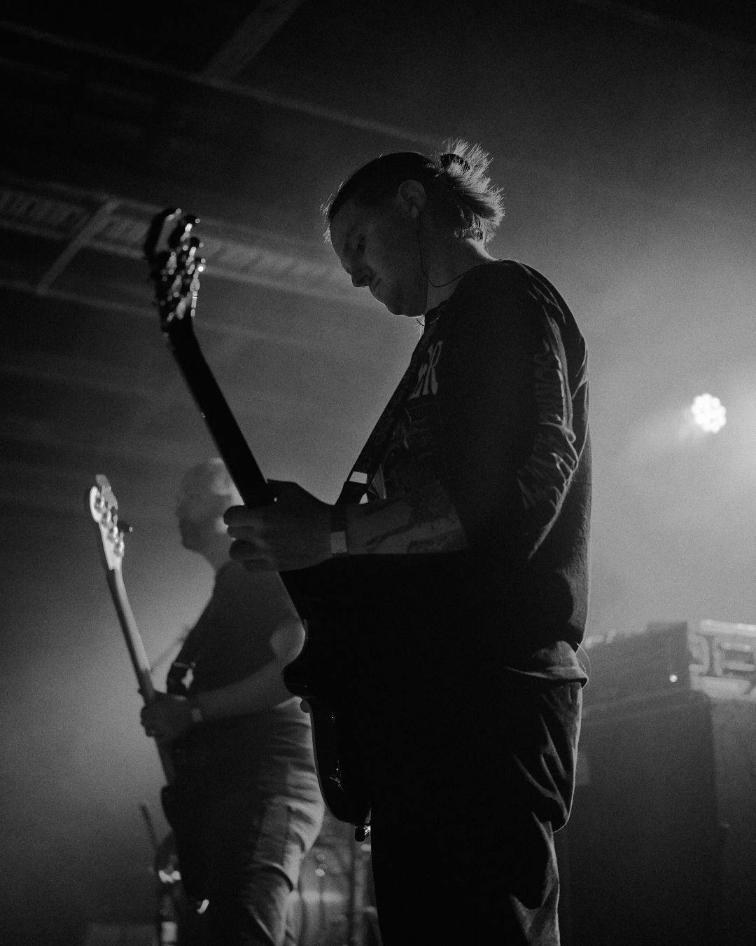 A black and white image of slowcuts guitarist and bassist. A low angle photo makes them loom larger than life.