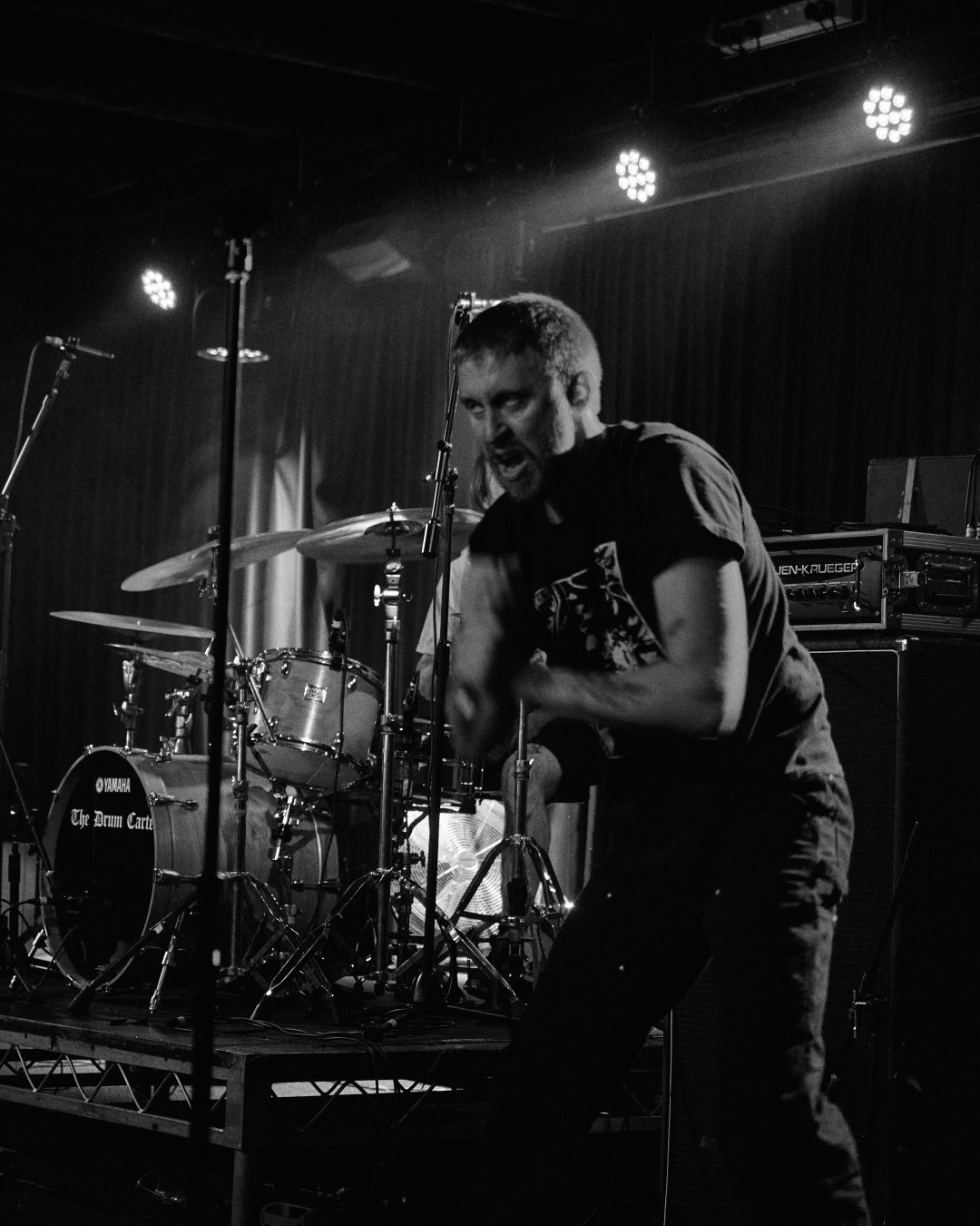 A black and white image of Cerebral Erosion's vocalist looking all scary and evil, with the drummer behind him.