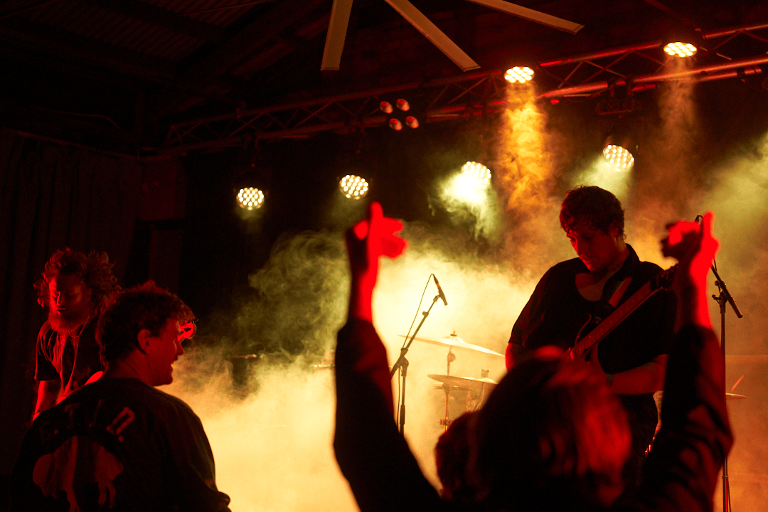 A crowd member incites more mayhem from Totally Unicorn as they are all bathed in red light, smoke fills the stage.