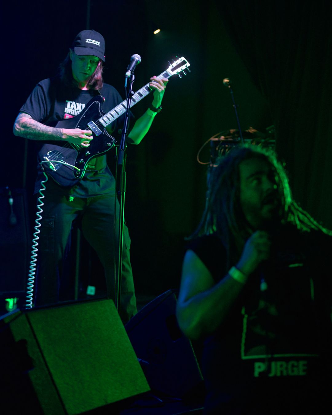 Vocalist joins the crowd, with the guitarist looming over them from on stage.