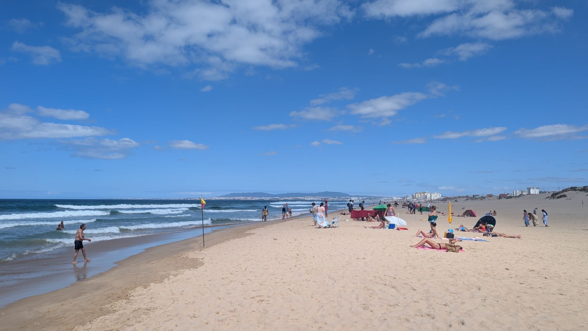 Beach scene in Lisbon. Surf and white sand. Lifesaving flags.